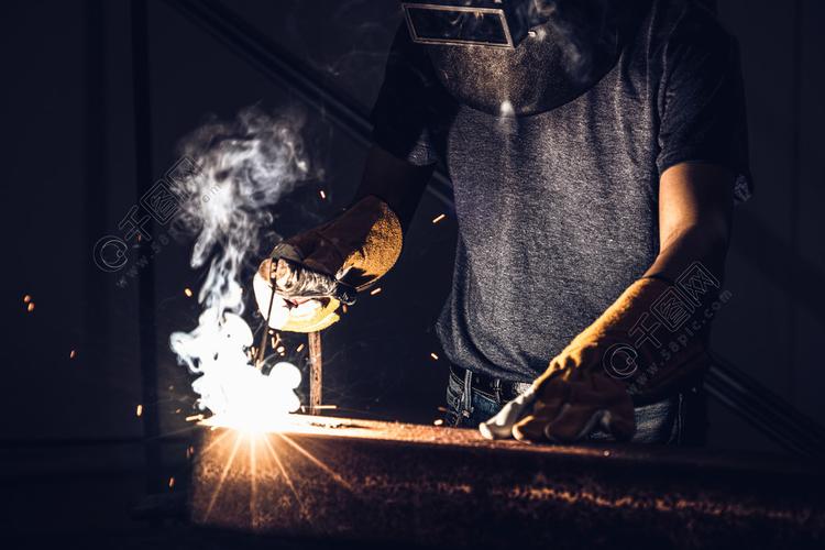 在工厂焊接钢同时佩戴安全设备通过手工技能劳动概念的金属制品制造?